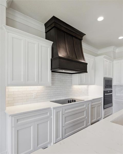 Kitchen featuring white cabinetry, premium range hood, tasteful backsplash, and black appliances