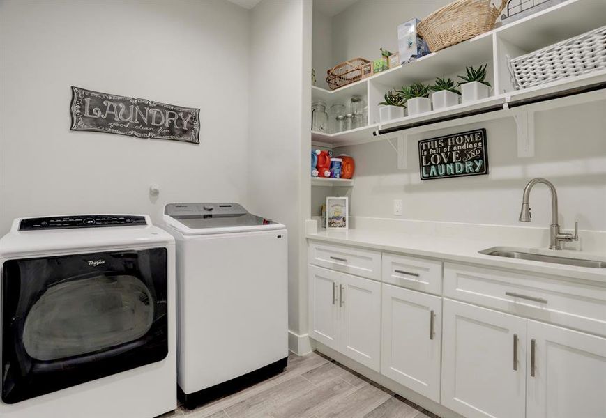 ENJOY THE CONVENIENCE OF THIS SPACIOUS LAUNDRY ROOM, DESIGNED FOR EFFICIENCY WITH MODERN APPLIANCES, AMPLE CABINETRY, AND A PRACTICAL SINK AREA, MAKING LAUNDRY TASKS EASIER AND MORE ENJOYABLE.