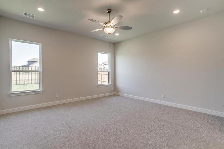 Carpeted empty room with ceiling fan and a wealth of natural light