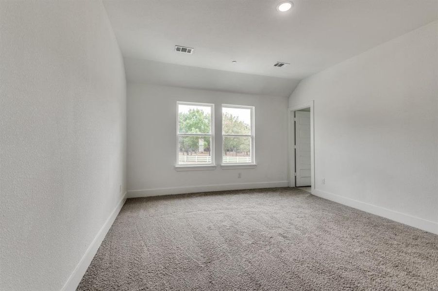 Empty room featuring carpet flooring and vaulted ceiling