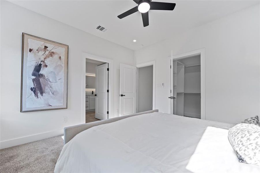 Bedroom featuring a walk in closet, carpet flooring, ensuite bathroom, ceiling fan, and a closet