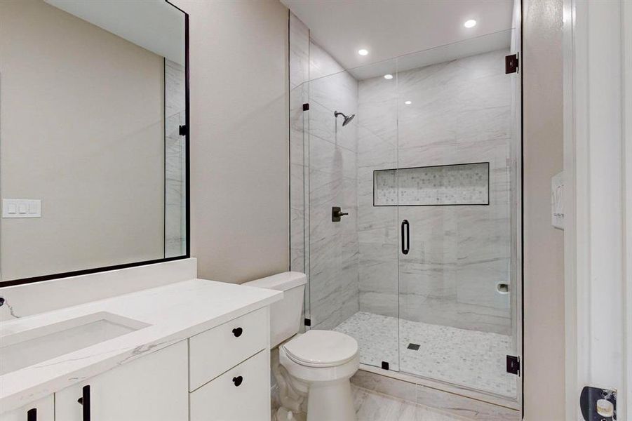 Bathroom with vanity, toilet, and a shower with door