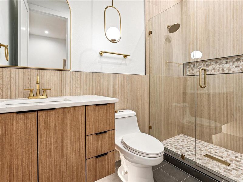 Bathroom featuring vanity, a shower with shower door, toilet, and tile patterned flooring