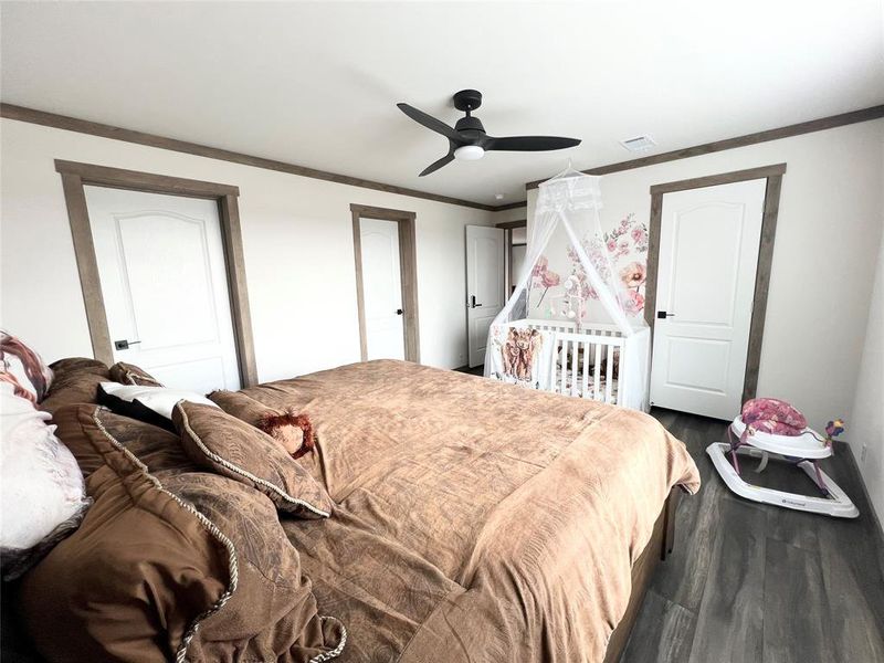 Bedroom featuring crown molding, dark wood-type flooring, and ceiling fan