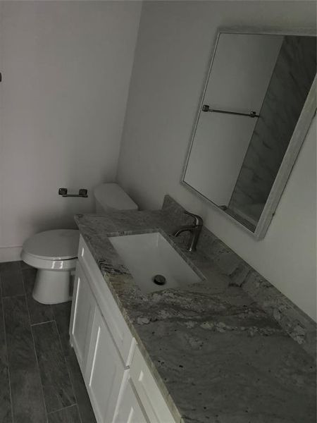 Half Bathroom featuring tile patterned floors, toilet, and vanity