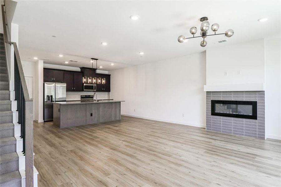 Open living room with, designer fixtures, fireplace and light wood plank flooring