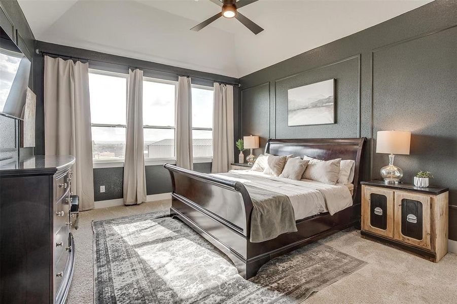 Bedroom with vaulted ceiling, light carpet, multiple windows, and ceiling fan