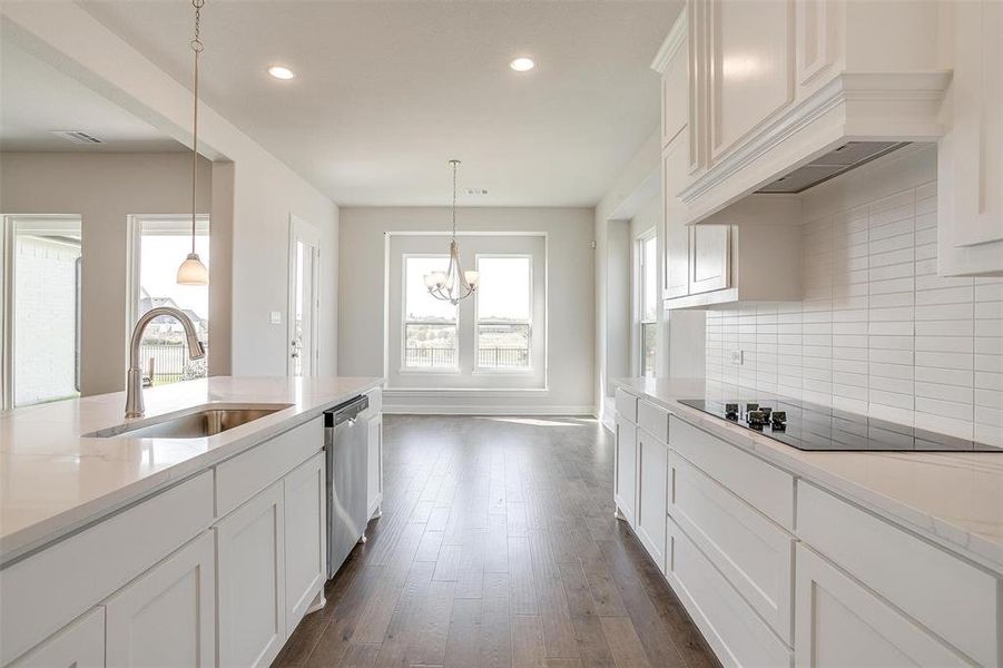 Kitchen featuring black electric stovetop, sink, stainless steel dishwasher, a notable chandelier, and dark hardwood / wood-style floors