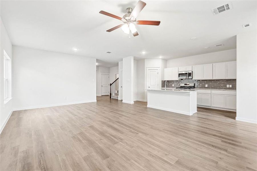 Unfurnished living room featuring sink, light wood-type flooring, and ceiling fan