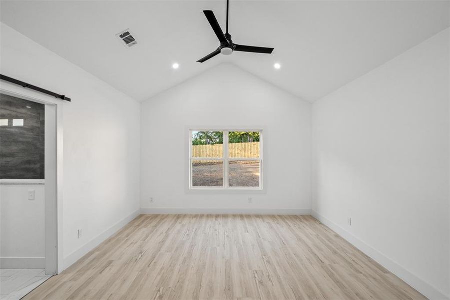 Empty room with lofted ceiling, ceiling fan, and light hardwood / wood-style floors