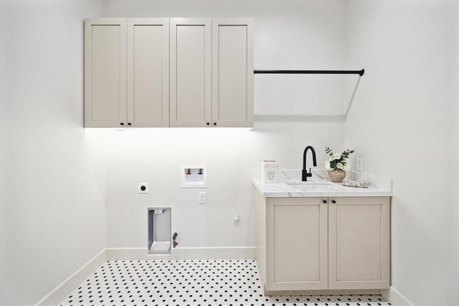 The laundry room has a sink, drying bar and storage plus classic black and white tile floor. This room is as functional as it is pretty.