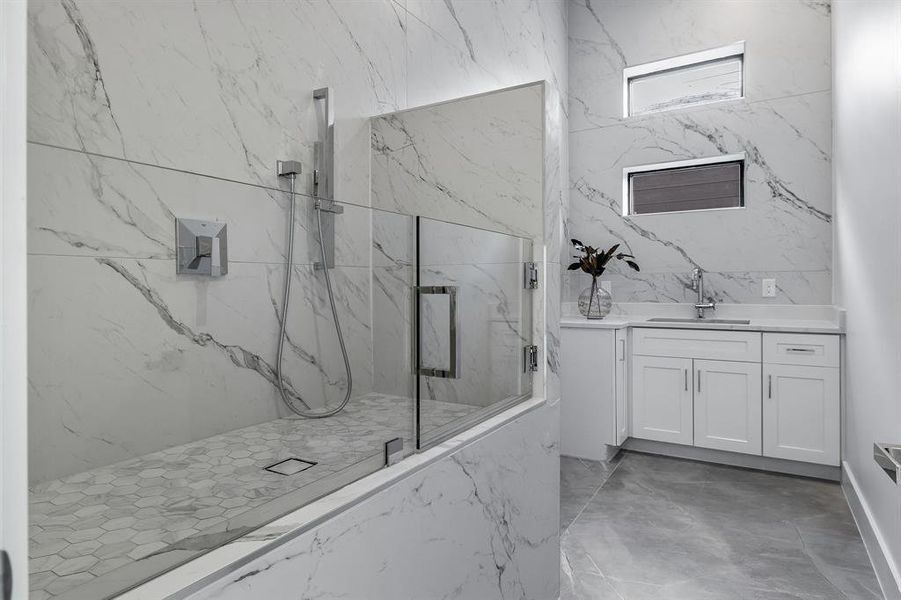 Bathroom featuring a shower with shower door and vanity