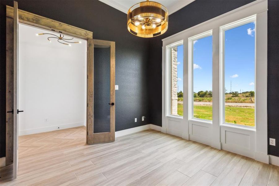 Unfurnished room with a notable chandelier, crown molding, and french doors