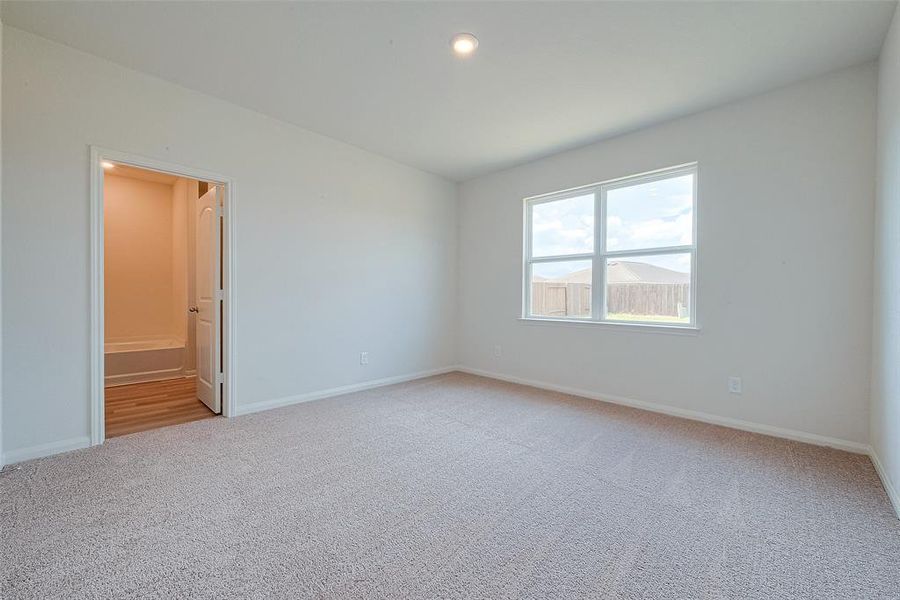 Room with beige carpet, white walls, a window, and an open door leading to another room.