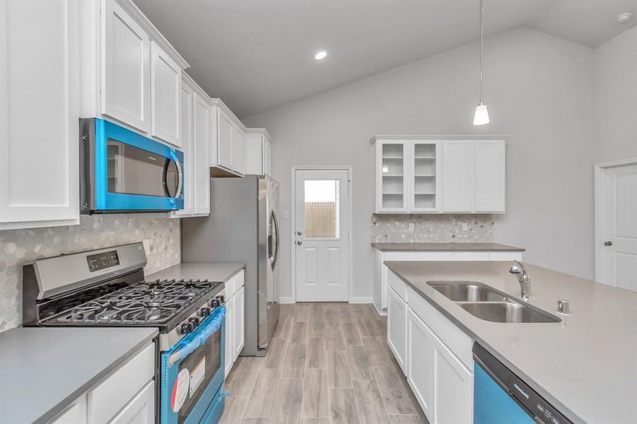 Enjoy the perfect balance of style and efficiency in this modern kitchen. The high-end stainless steel appliances, including a double-door refrigerator, microwave, and gas range, are complemented by durable quartz countertops and sleek cabinetry. **This image is from another Saratoga Home - Wren floorplan.**