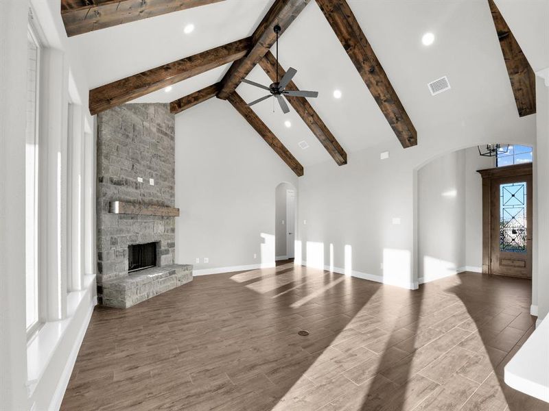 Unfurnished living room with a fireplace, ceiling fan, hardwood / wood-style flooring, beam ceiling, and high vaulted ceiling