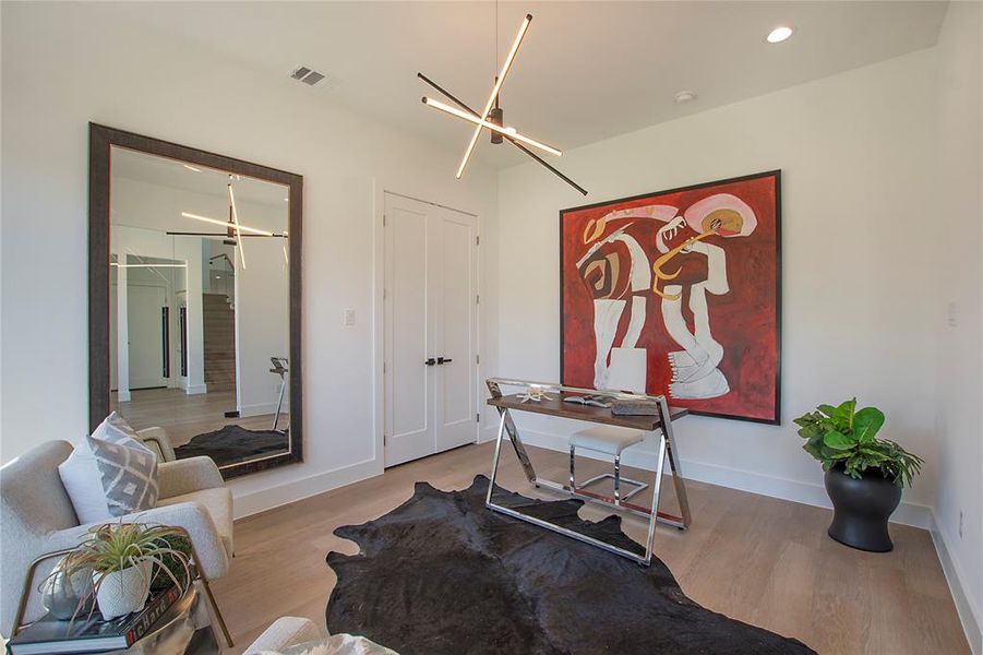 Home office with a notable chandelier and light wood-type flooring