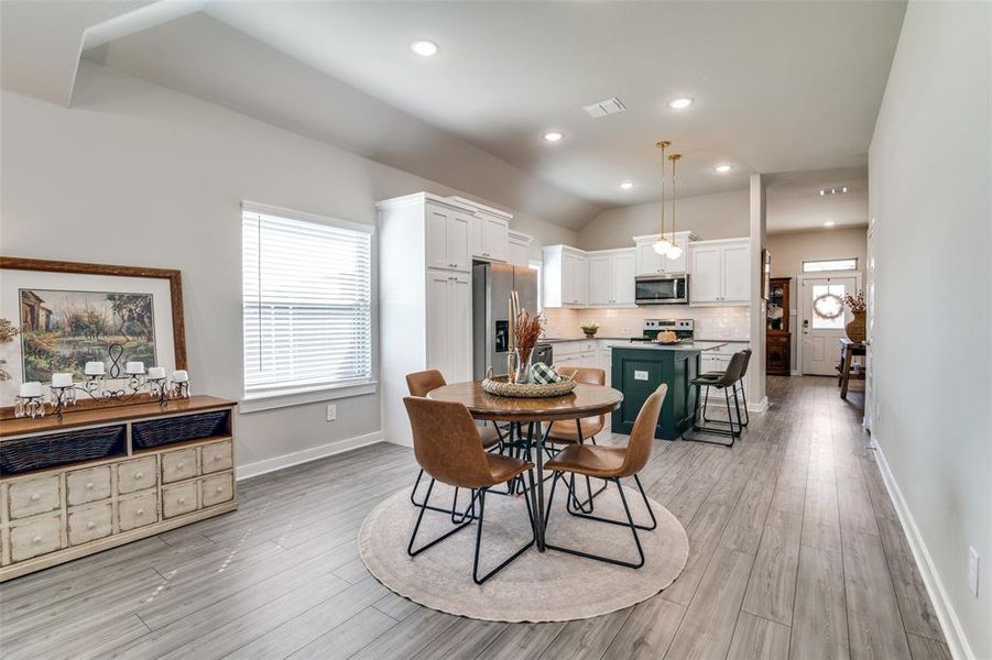 Dining space with vaulted ceiling and light hardwood / wood-style flooring