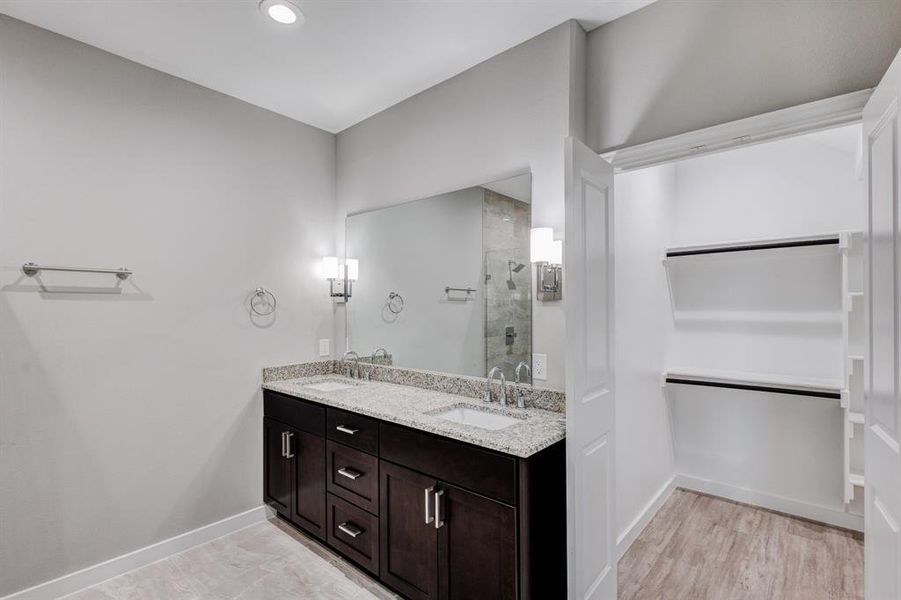 Bathroom with a shower with shower door, hardwood / wood-style floors, and double vanity