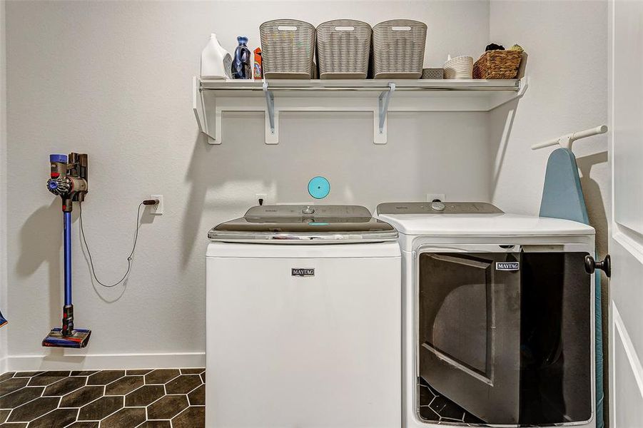 This laundry room was customized to include room for a large hall tree to drop coats and back packs, fridge and washer and dryer. It offers gorgeous hexagon tile and elevated light package.