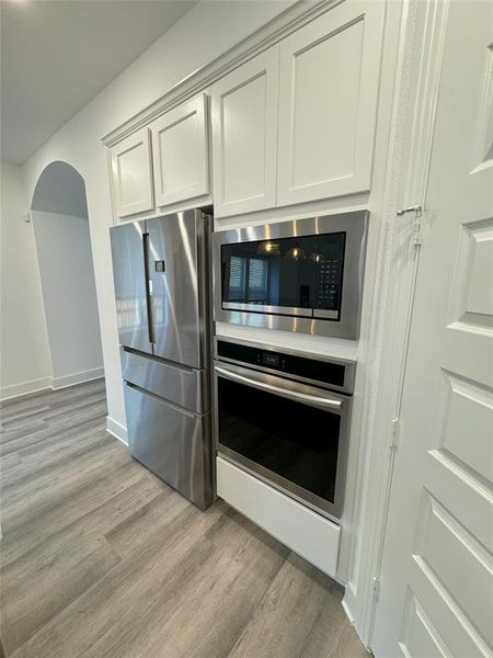 Kitchen with light hardwood / wood-style floors and stainless steel appliances