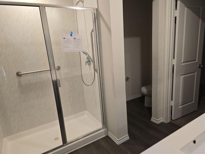 Bathroom with wood-type flooring, toilet, and an enclosed shower