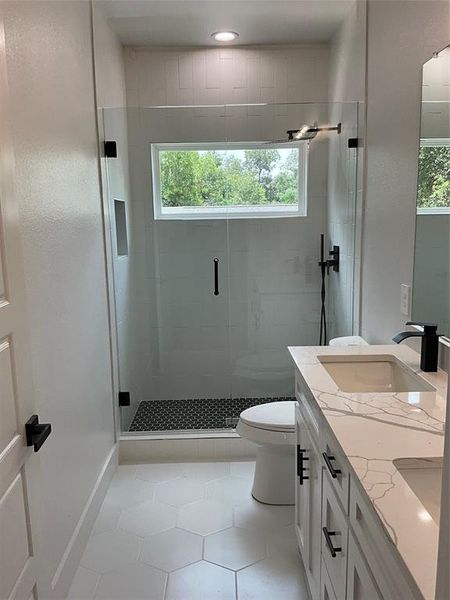 Bathroom with vanity, an enclosed shower, tile patterned flooring, and a healthy amount of sunlight