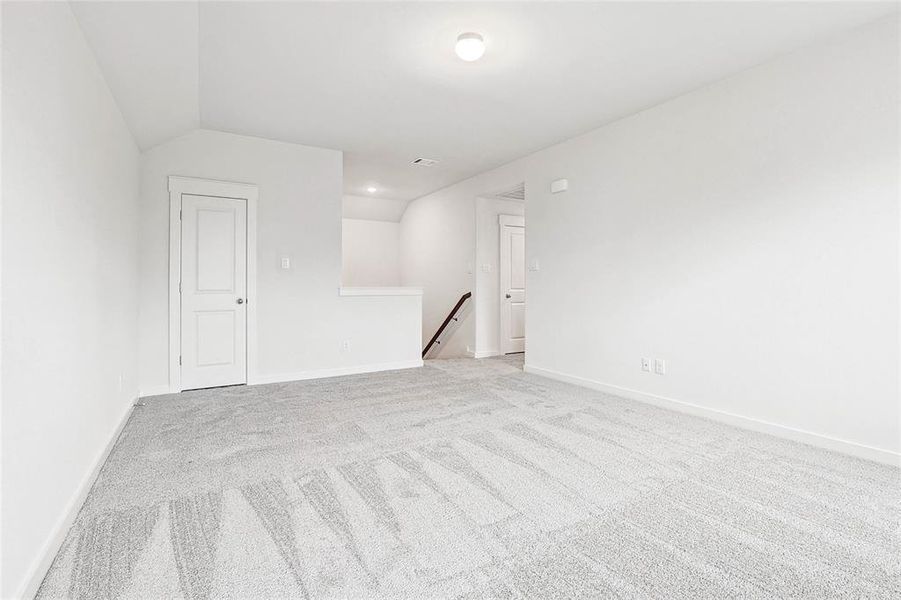 Unfurnished room featuring vaulted ceiling and light colored carpet