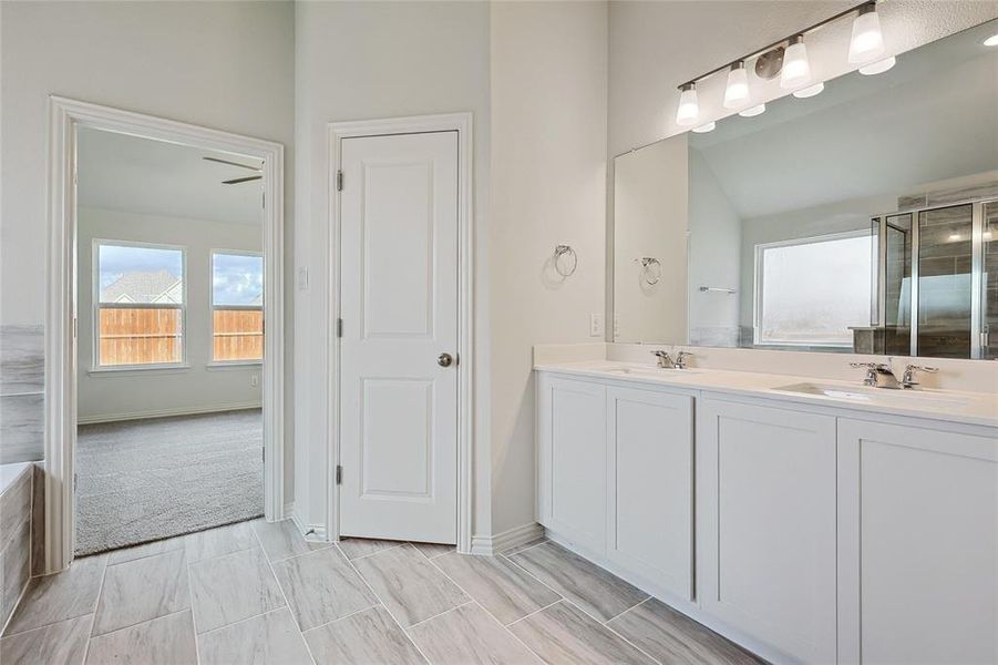 Bathroom with a bath to relax in, tile floors, lofted ceiling, and dual bowl vanity