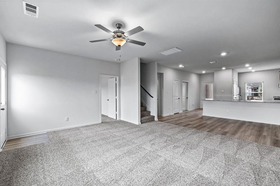 Unfurnished living room with light colored carpet and ceiling fan