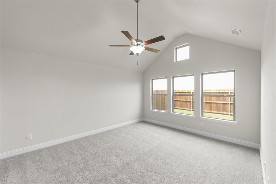 Carpeted spare room featuring high vaulted ceiling and ceiling fan