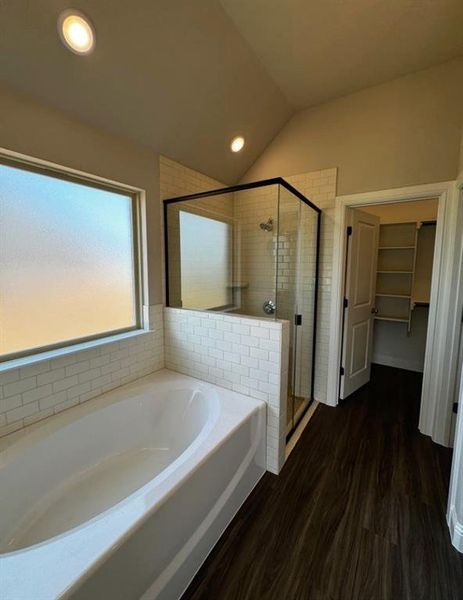 Bathroom with independent shower and bath, vaulted ceiling, and hardwood / wood-style flooring