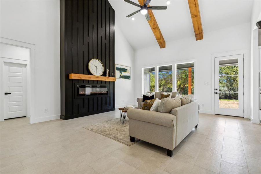 Living room with ceiling fan, beamed ceiling, plenty of natural light, and high vaulted ceiling