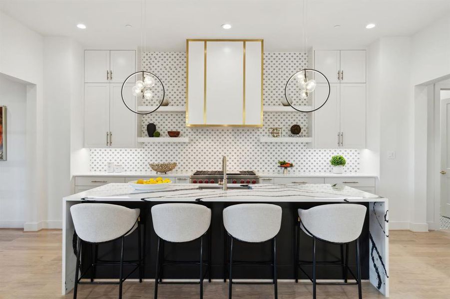 Kitchen featuring white cabinets, tasteful backsplash, light wood-type flooring, and a center island with sink