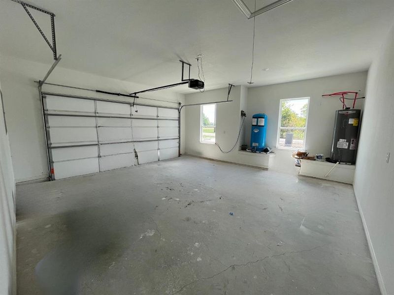 Garage featuring a garage door opener and electric water heater