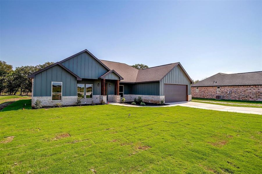 View of front of property with a garage and a front lawn