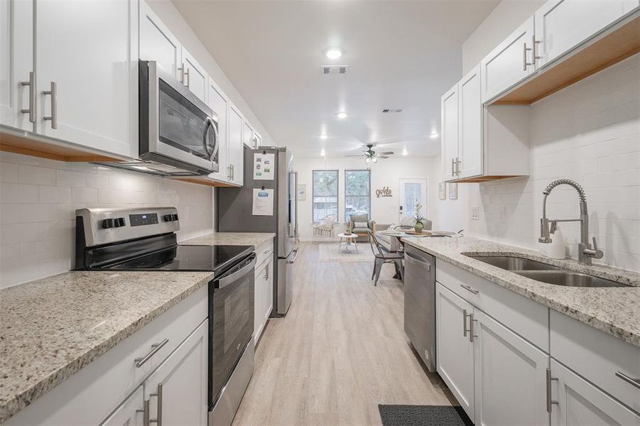 Kitchen featuring appliances with stainless steel finishes, sink, and white cabinets