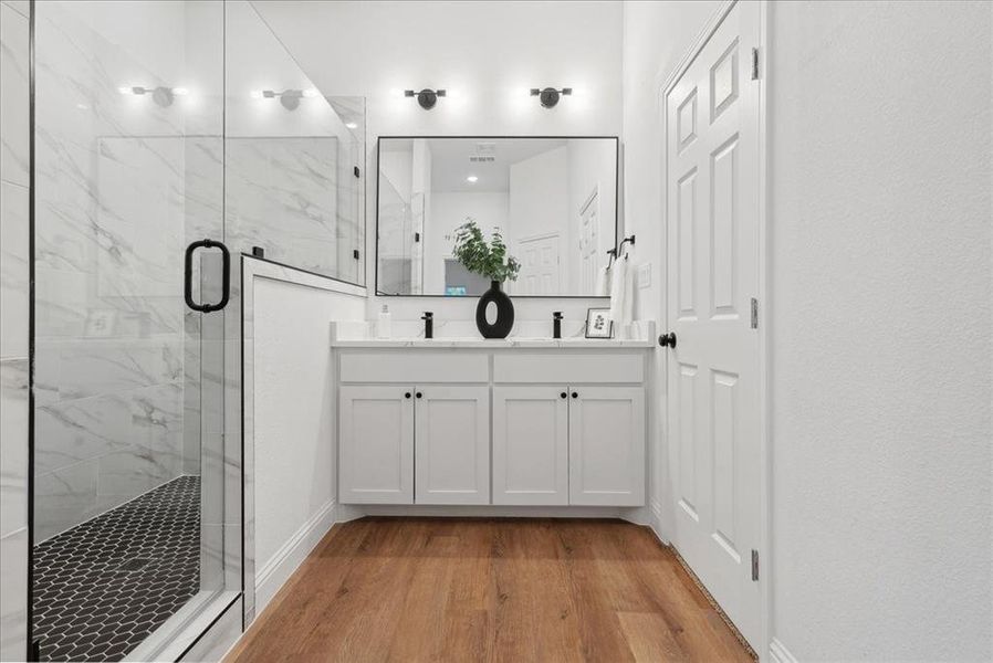 Bathroom with vanity, hardwood / wood-style flooring, and a shower with shower door