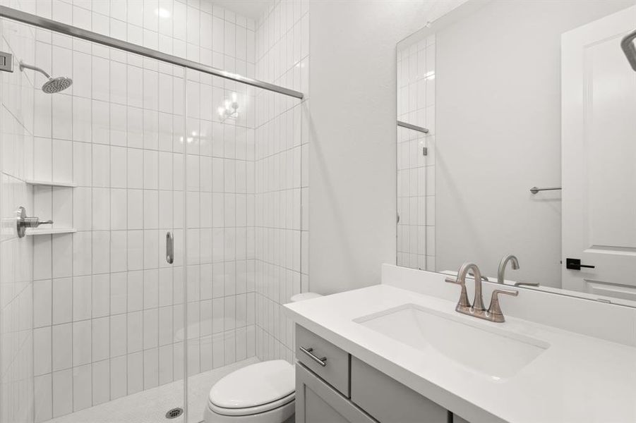 The second bedroom's bathroom includes a gorgeous tiled walk-in shower, toilet, and sink vanity, providing a modern and efficient space for daily use.