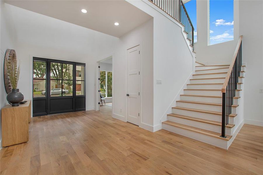 Entrance foyer with light wood-type flooring and a towering ceiling