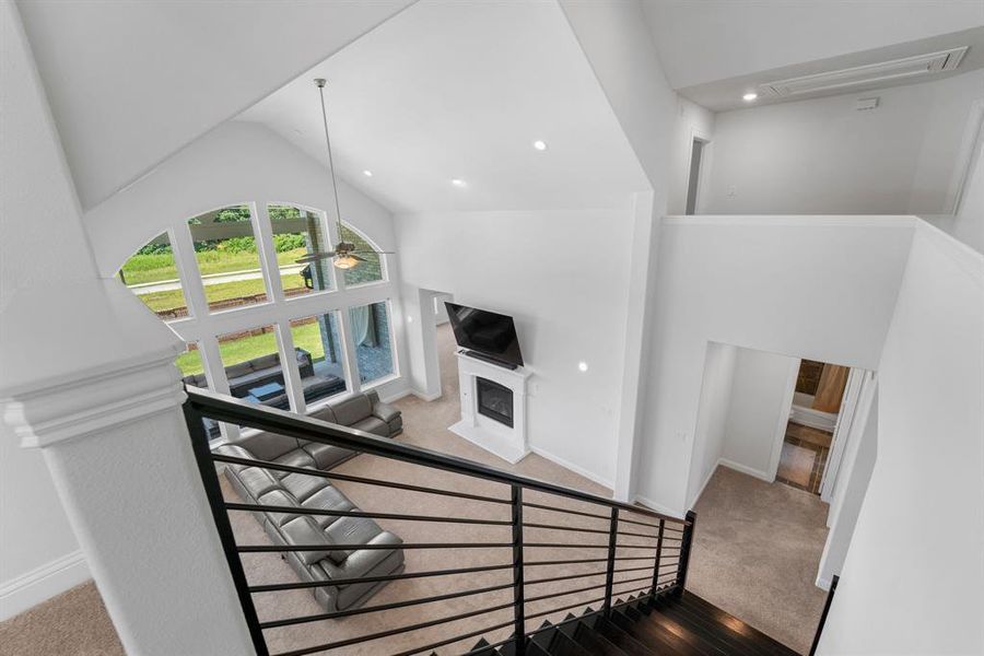 Staircase with high vaulted ceiling, ceiling fan, and carpet floors