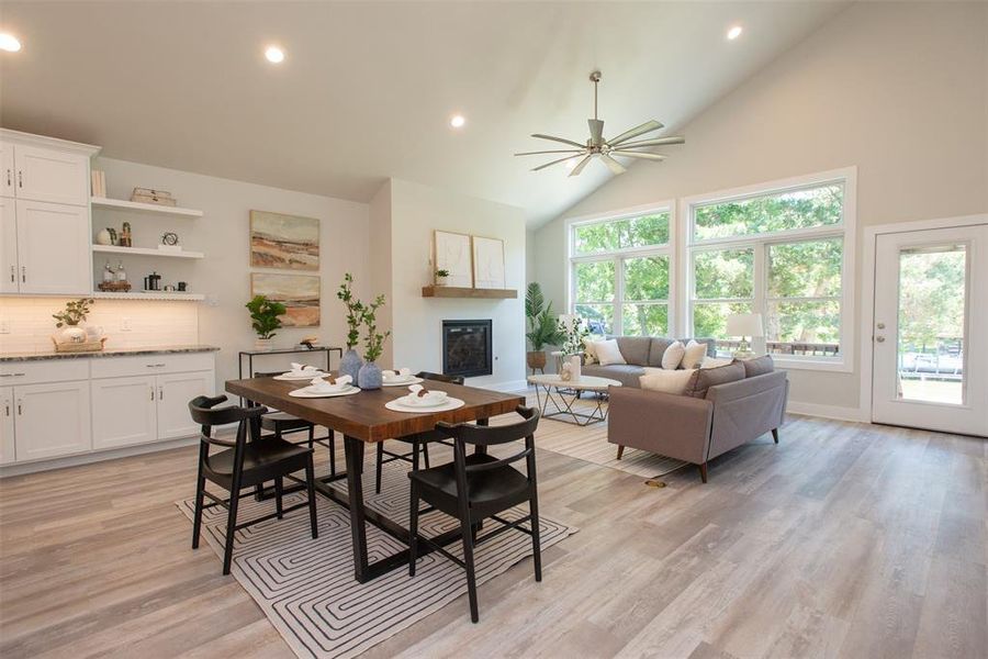 Dining room featuring high vaulted ceiling, ceiling fan, and light hardwood / wood-style flooring and large windows