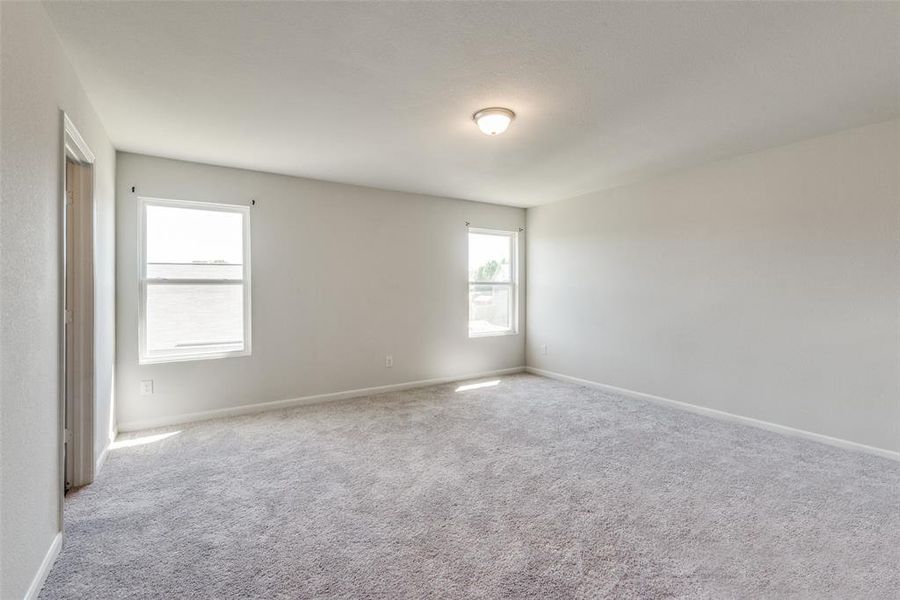 Empty room featuring light colored carpet and a wealth of natural light