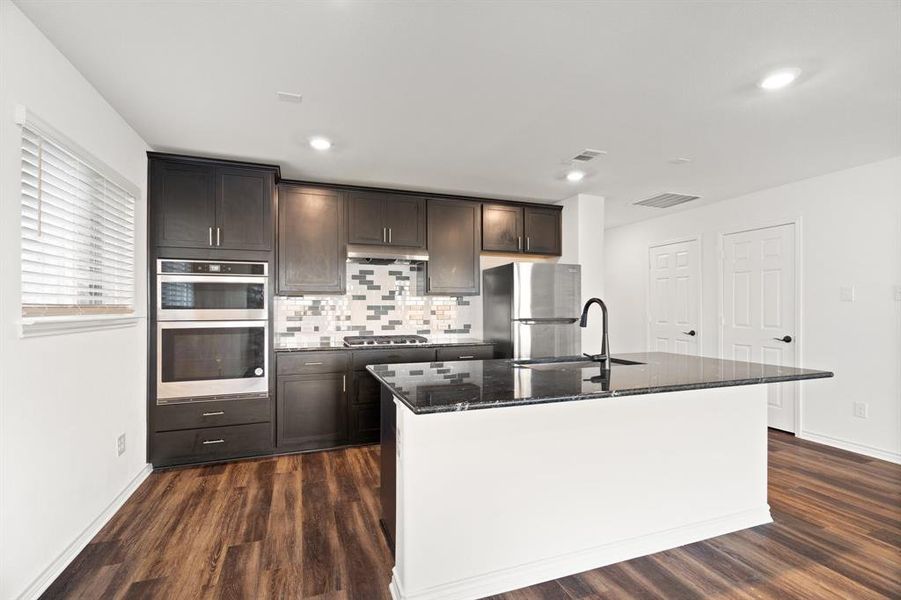 Kitchen with stainless steel appliances, a center island with sink, sink, and dark hardwood / wood-style flooring