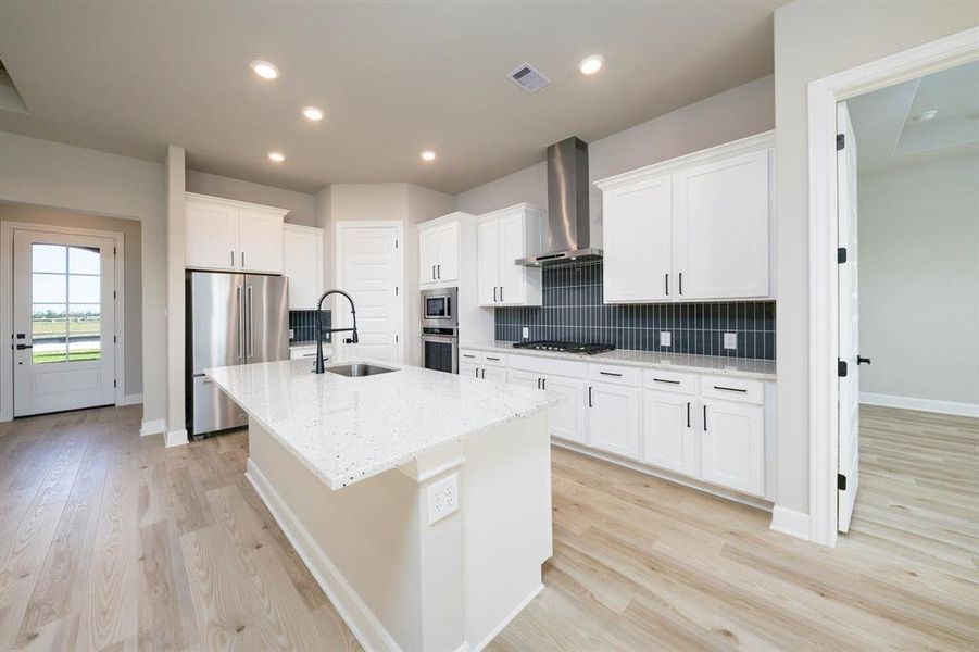 The kitchen boasts a spacious island, complemented by pristine white cabinets and a stunning backsplash, creating an inviting and elegant space.