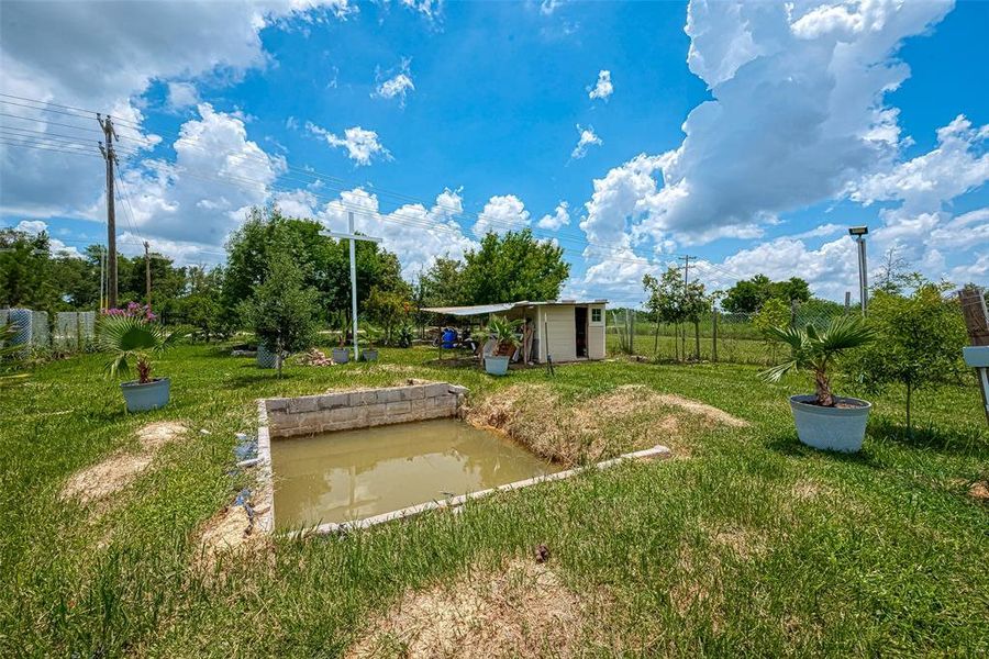 Another shed is located by the pond, offering additional storage or a quiet retreat by the water's edge.