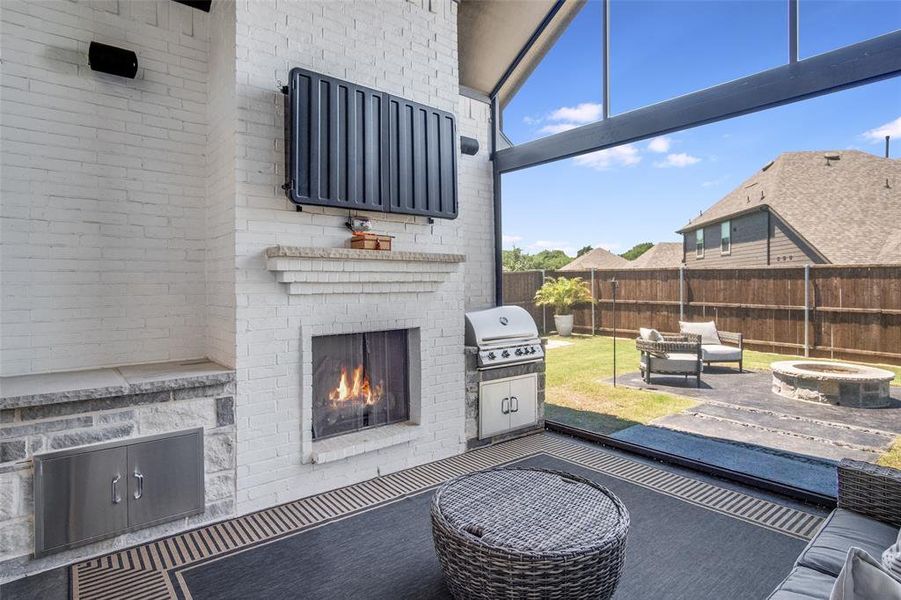 View of terrace with a fire pit, an outdoor brick fireplace, and grilling area