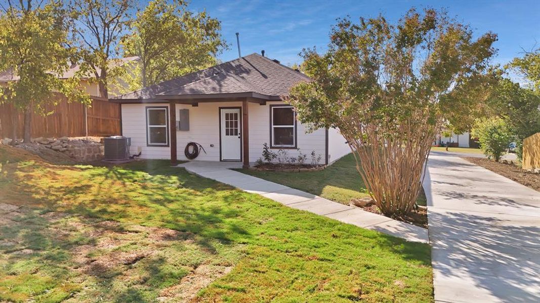 View of front of house featuring central AC and a front yard