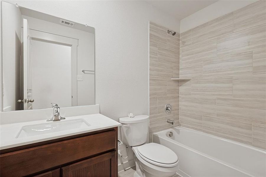 Full bathroom featuring toilet, tiled shower / bath, and vanity