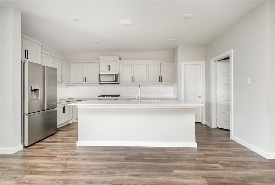 Kitchen featuring sink, appliances with stainless steel finishes, light wood-type flooring, and a kitchen island with sink